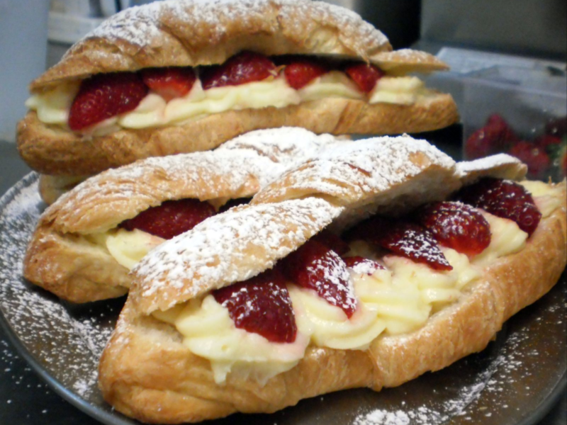 Croissants filled with cream and strawberries, dusted with powdered sugar.