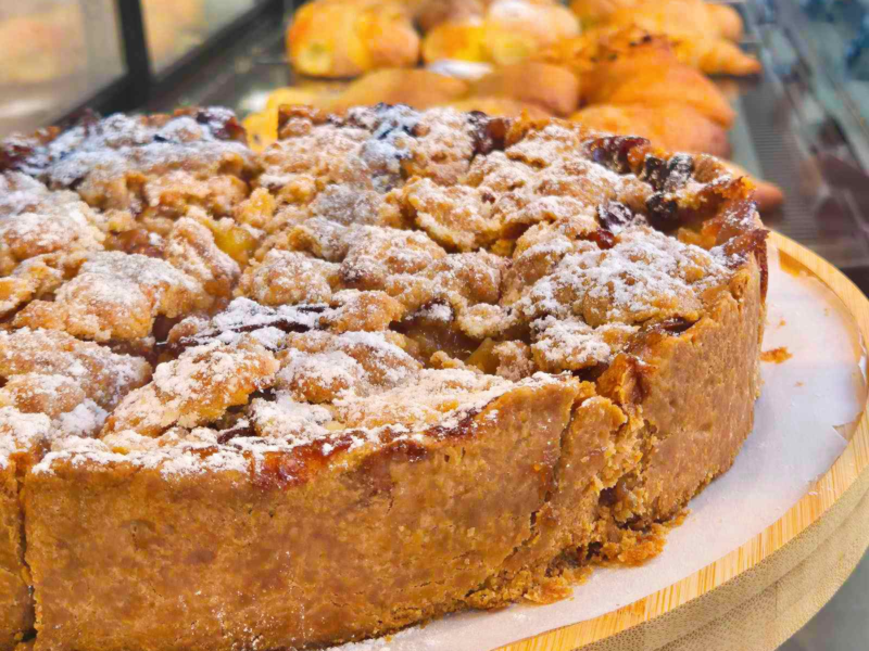 Close-up of a rustic apple crumble pie dusted with powdered sugar