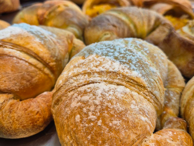 Close-up of freshly baked croissants dusted with powdered sugar.