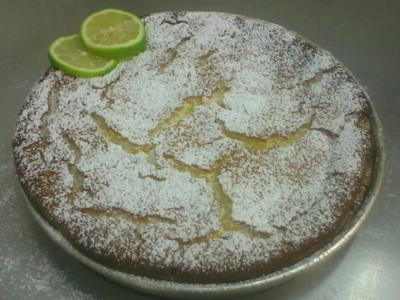 Lemon cake dusted with powdered sugar and garnished with lime slices.