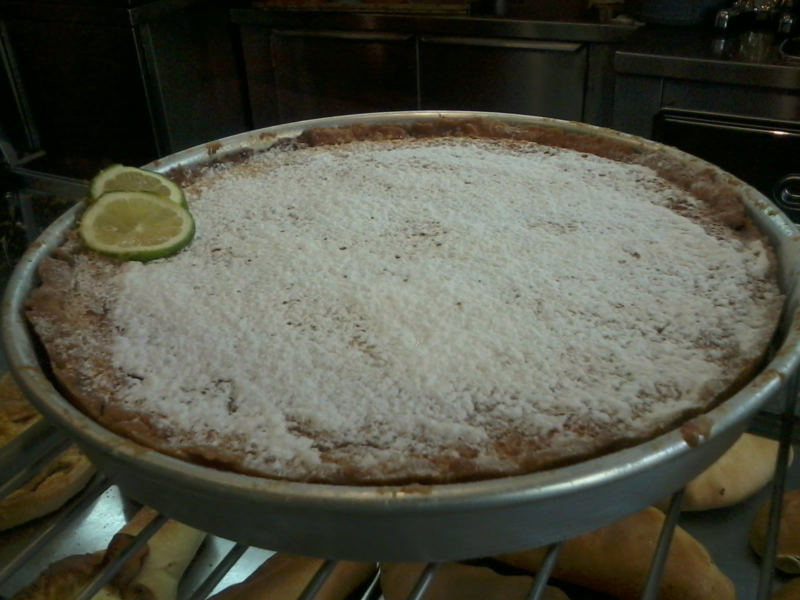 Lemon pie dusted with powdered sugar, garnished with lime slices